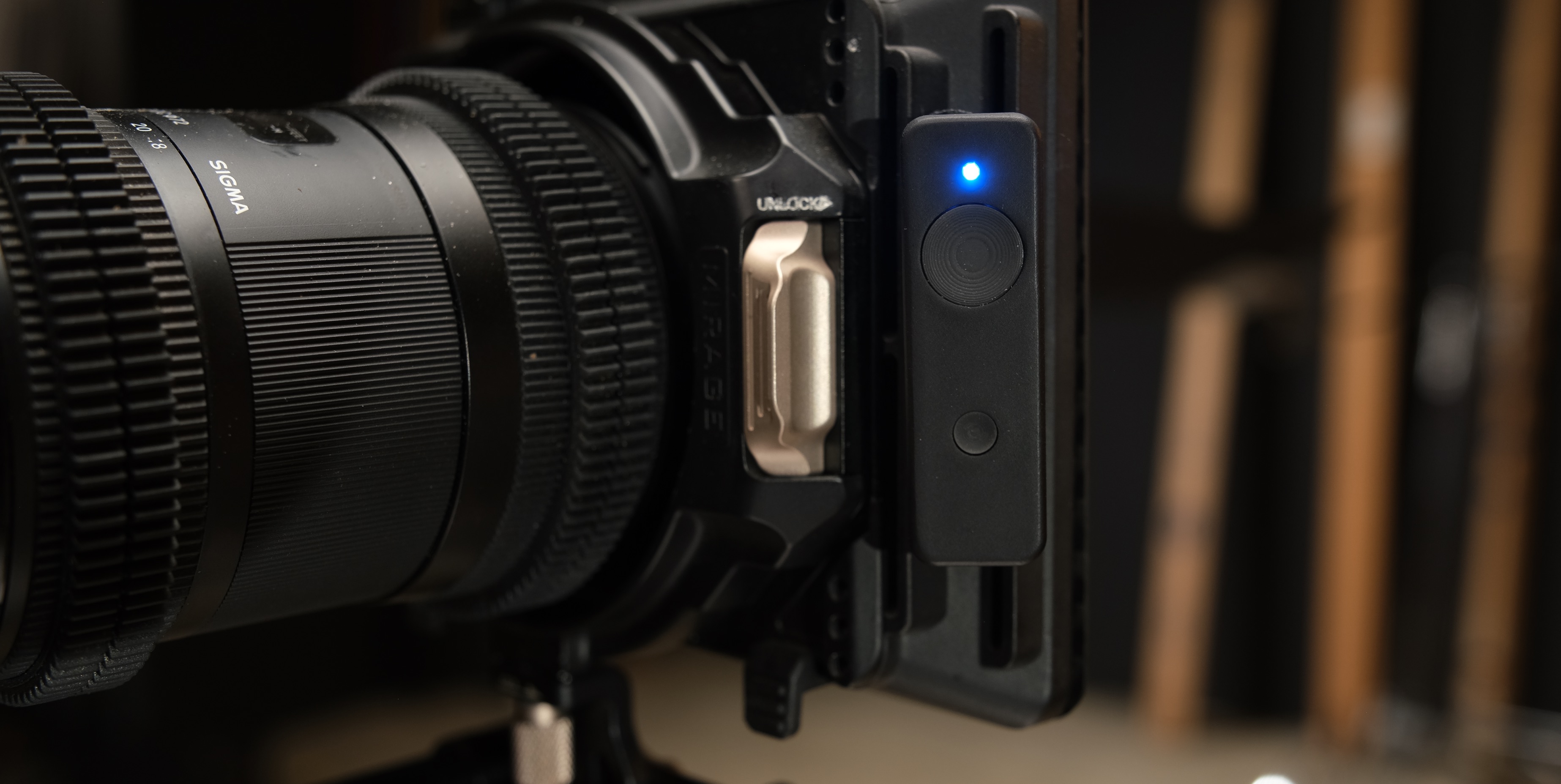 Marker Maker TX clamped to a cine rig next to a Sigma lens, blue status LED lit